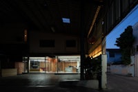 a warehouse at night with a building in the background